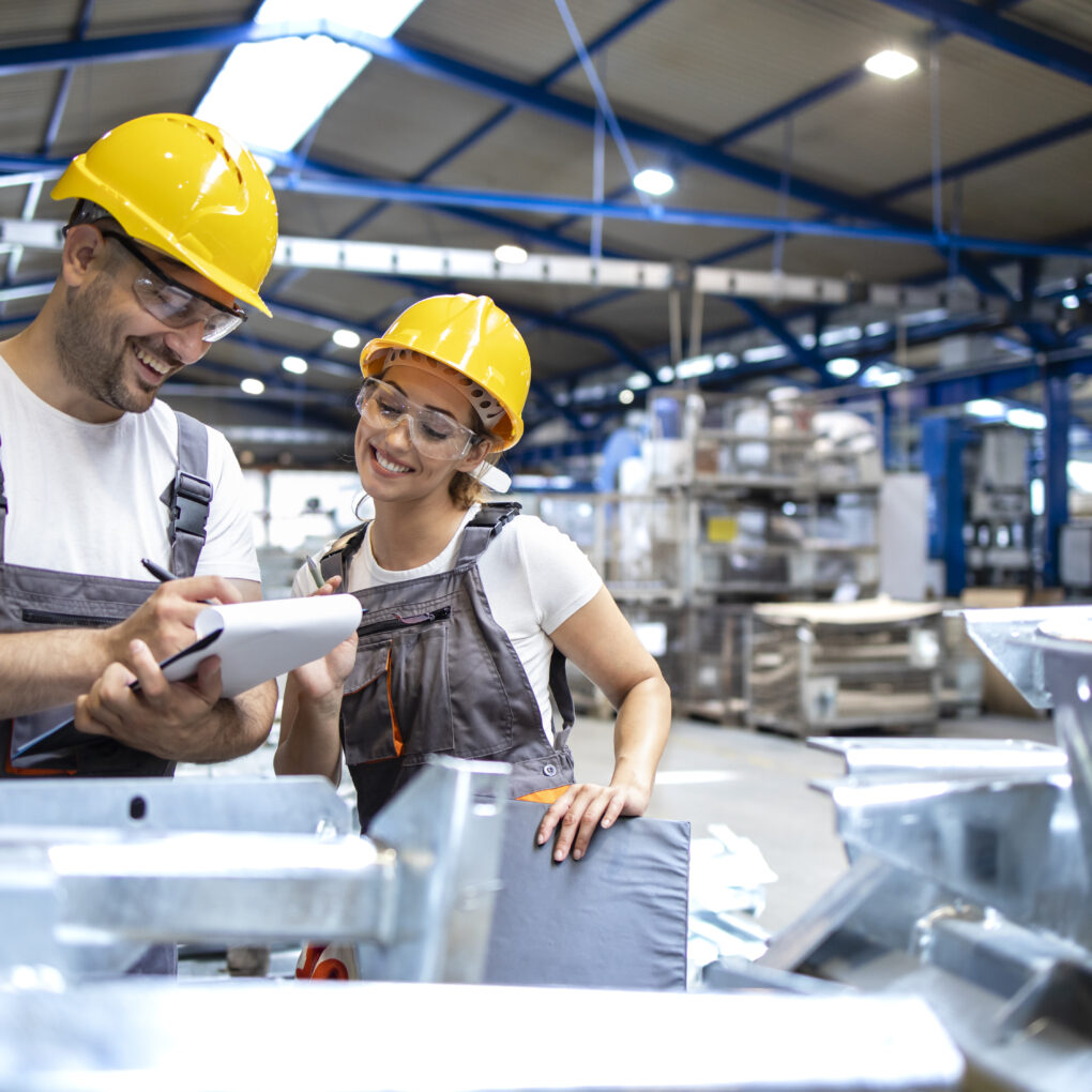 Factory workers checking quality of products in large industrial hall.